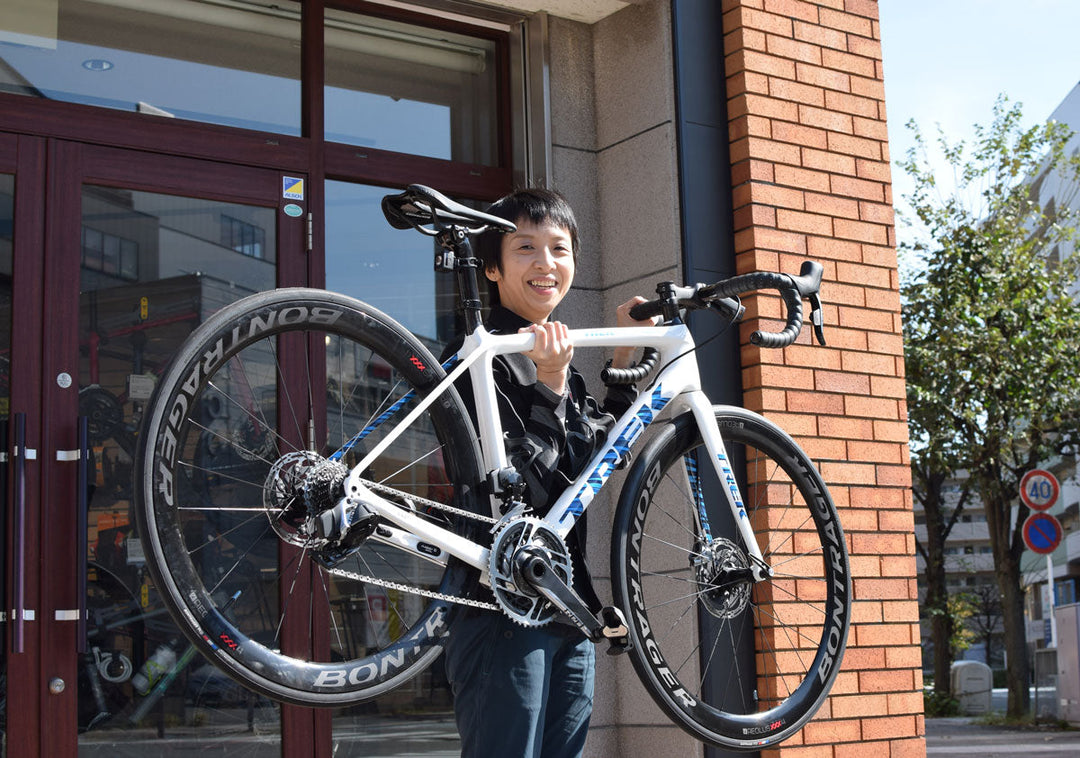 白いTREKロードバイクを片手で持つ人