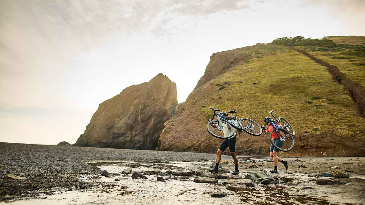 バイクを担いで沢をわたるグラベルライダー
