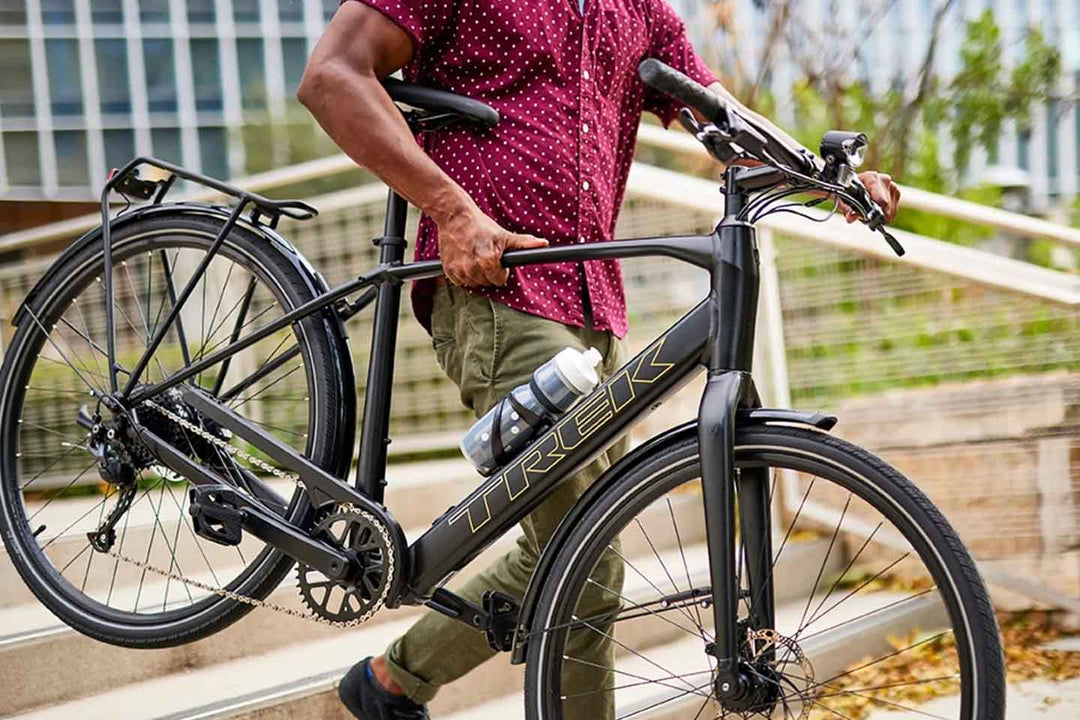 FX+2 電動アシストクロスバイクを持ち上げて階段を降りる男性