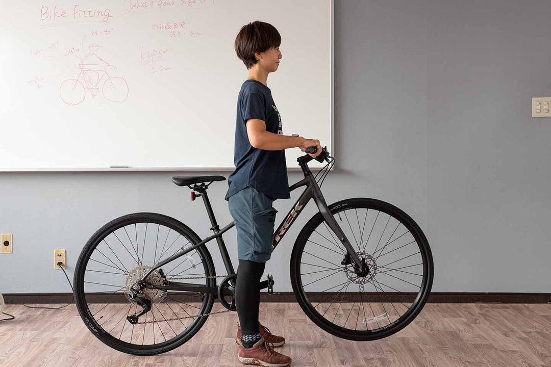 トップチューブにまたがってハンドルを持ちあげている様子