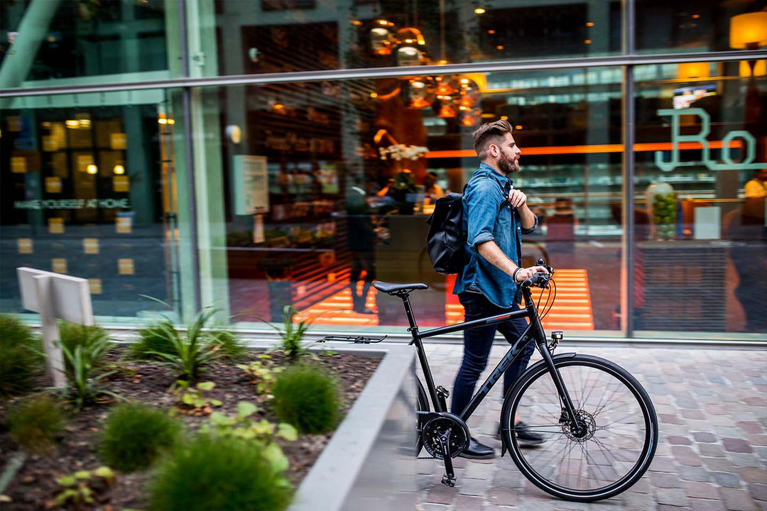 クロスバイクを降りて歩道を押して歩くイメージ写真。