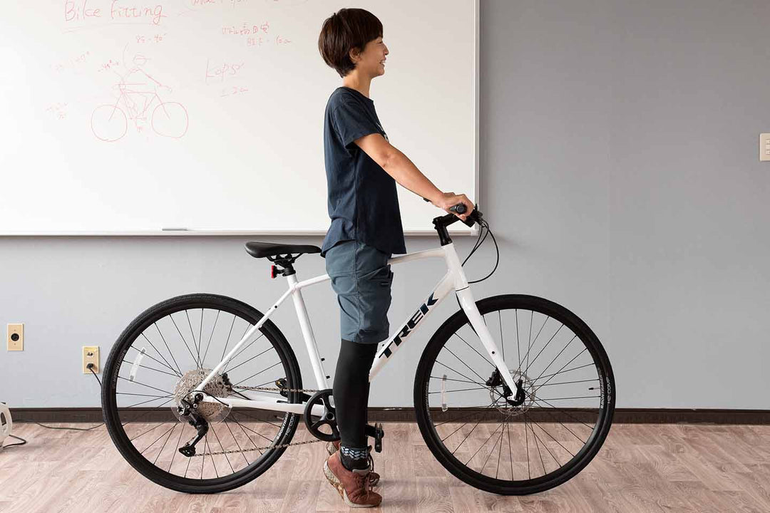 サイズの大きすぎるクロスバイクのトップチューブにまたがってつま先立ちになっている様子