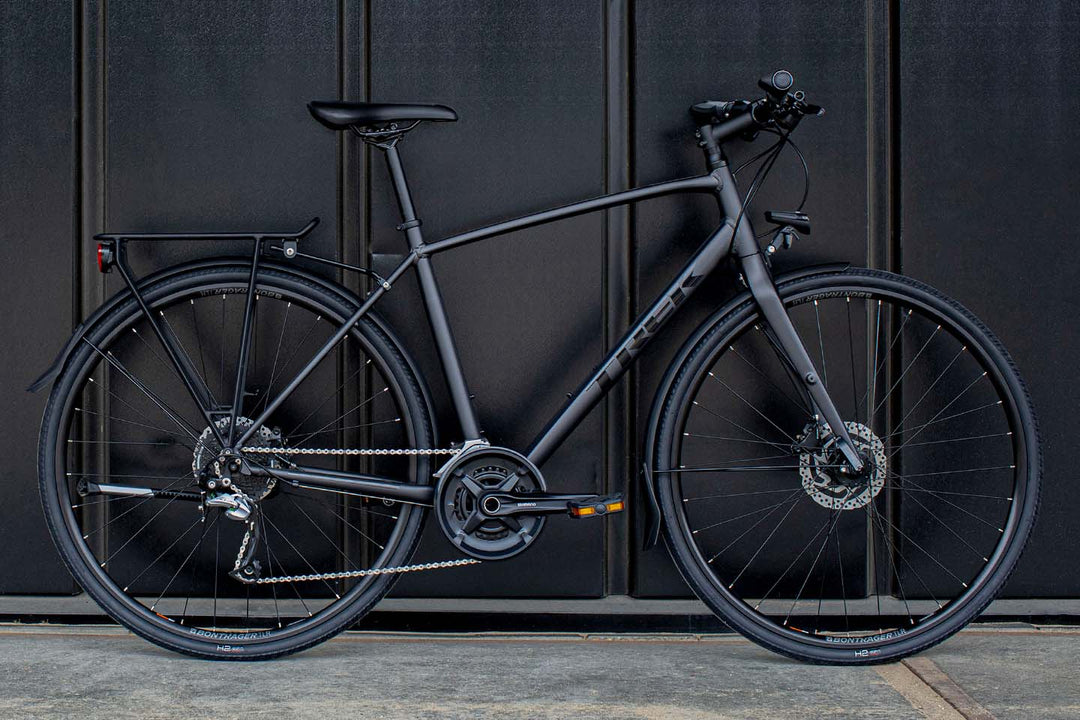 黒い壁面に立てかけられたマットブラックカラーのシックなクロスバイクの写真