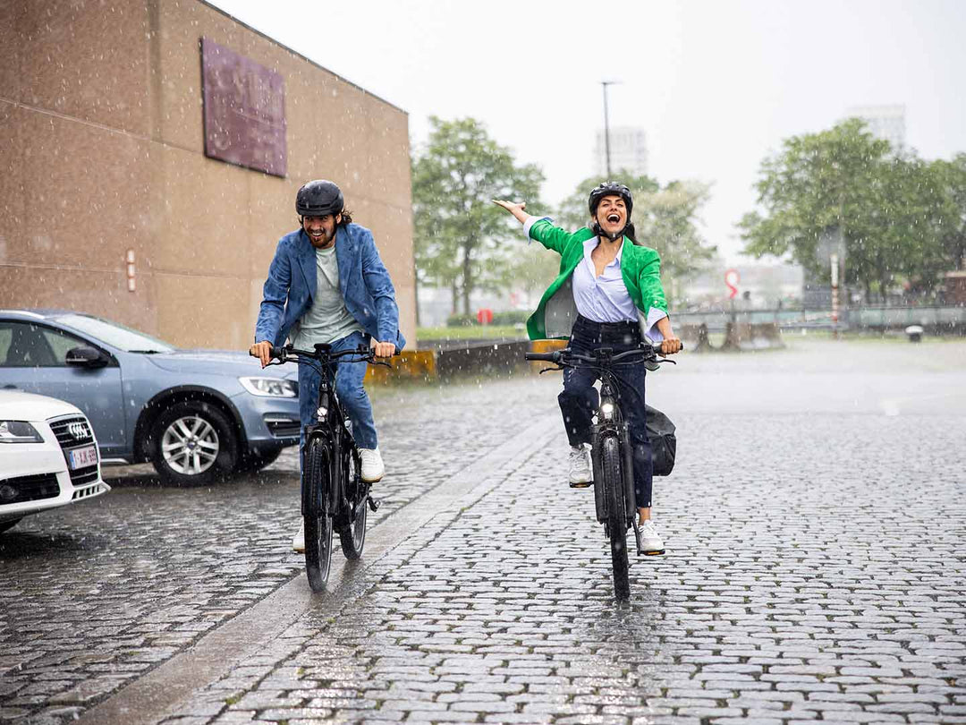 片手を上げて雨を楽しみながら走るサイクリストの写真