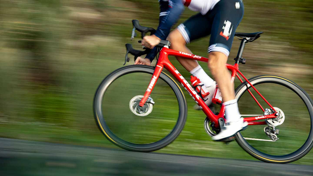 ものすごいスピードで立ち漕ぎで走り抜けるディスクブレーキ搭載ロードバイクの写真