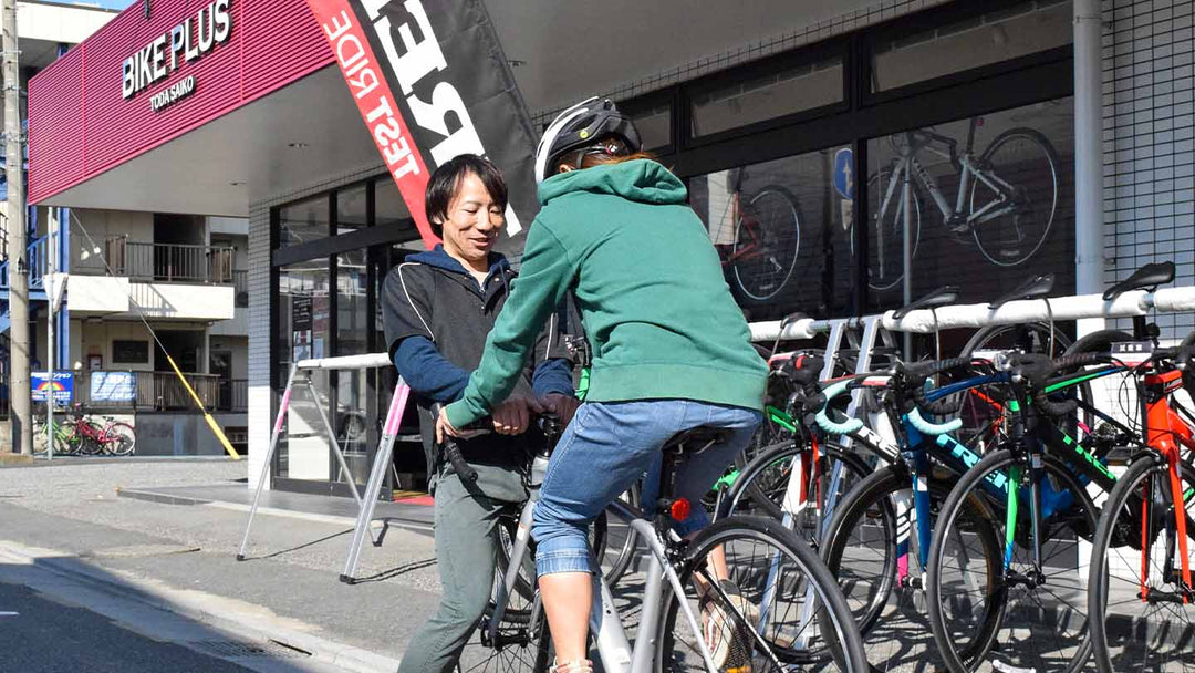 ロードバイクの試乗を前にサドルの高さをチェックするお客様とスタッフの様子