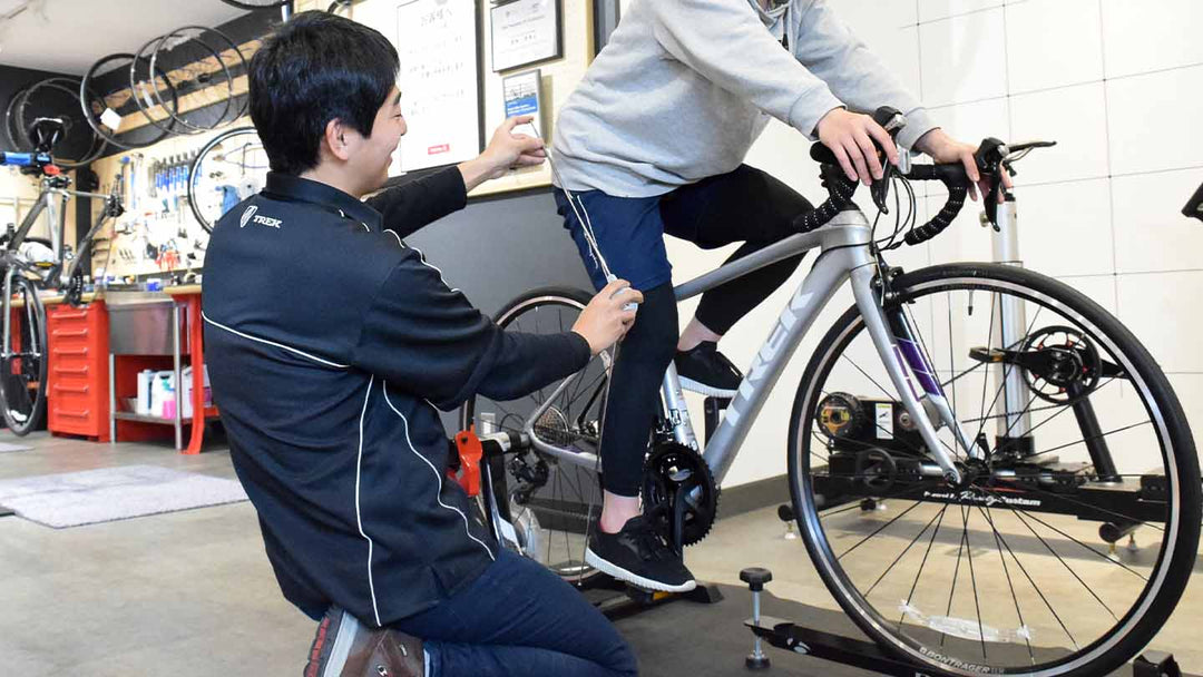 バイクフィッティング専門スペースで、膝関節の角度を計測しながら適切なサドルの高さをご案内している様子