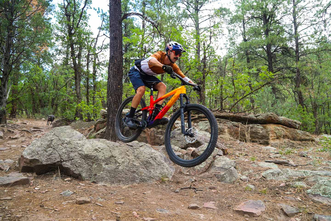 大きな岩のドロップオフを降りるフルサスペンションMTB