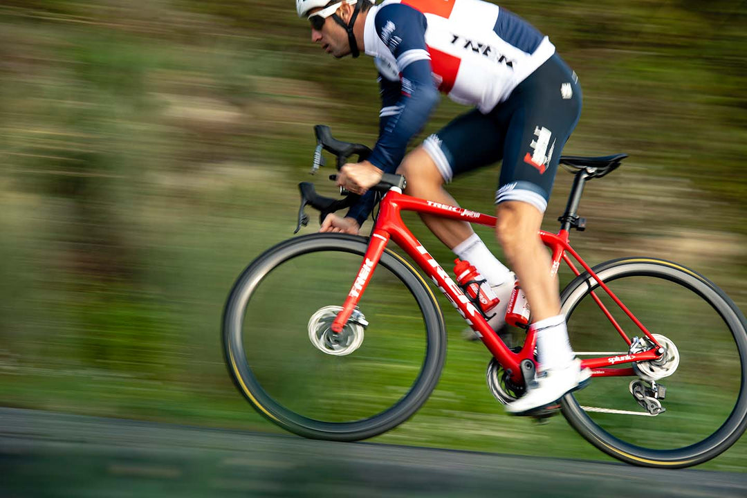 ダンシングをしながら高速で登りを登っていくロードバイクの写真