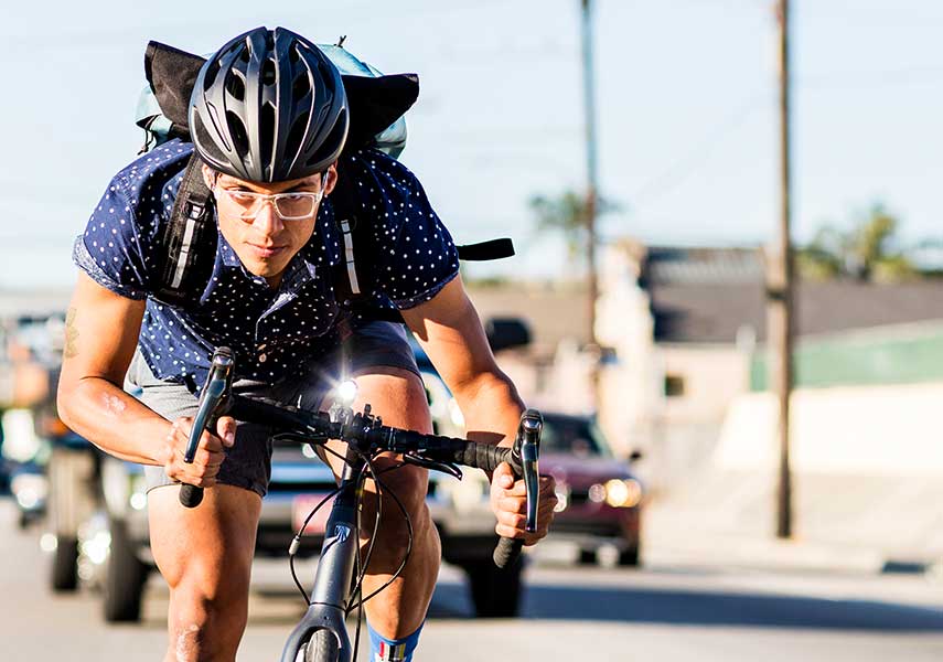 日中でも安全のためフロントライトを点灯し通勤するロードバイクの写真