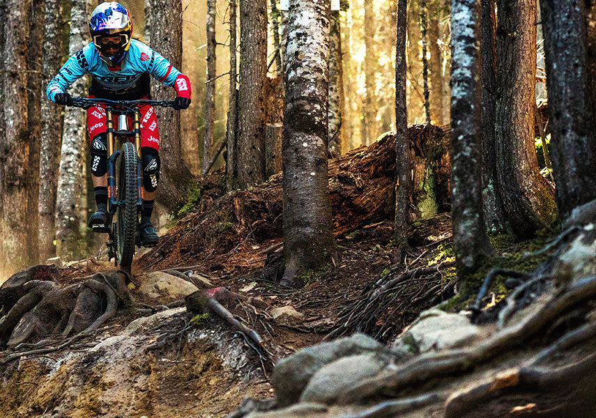 木の根や岩が転がるダートを降ってきたダウンヒルバイクを正面から撮影した写真