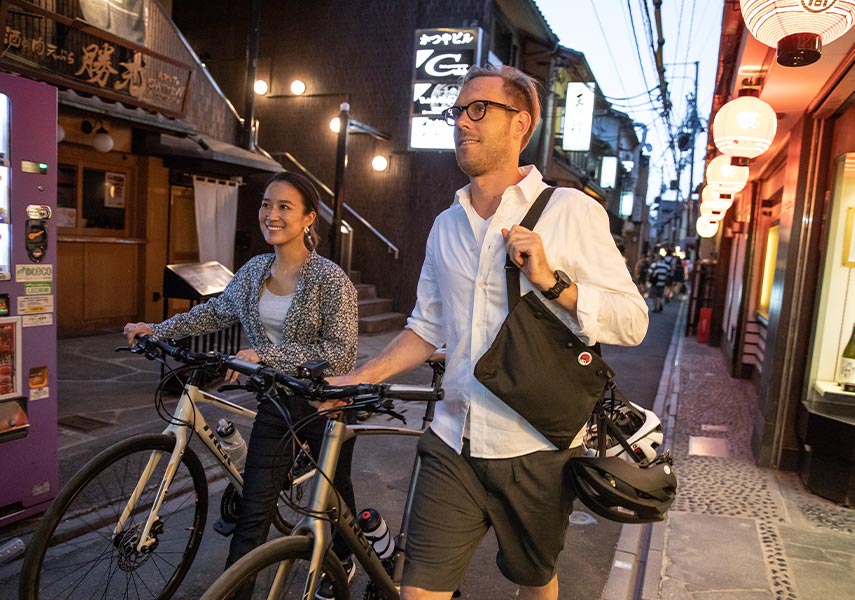 通勤帰りクロスバイクを降りて押しながら歩く二人のサイクリストの写真