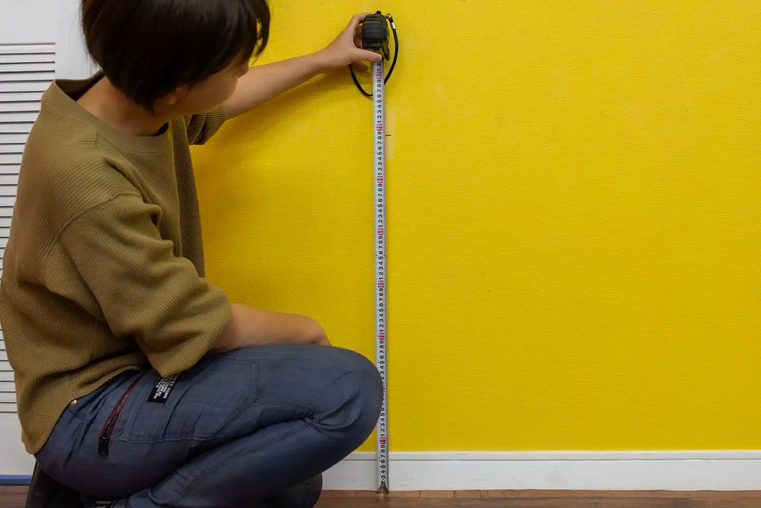 金属製のメジャーを使用して床から印までを測定する。