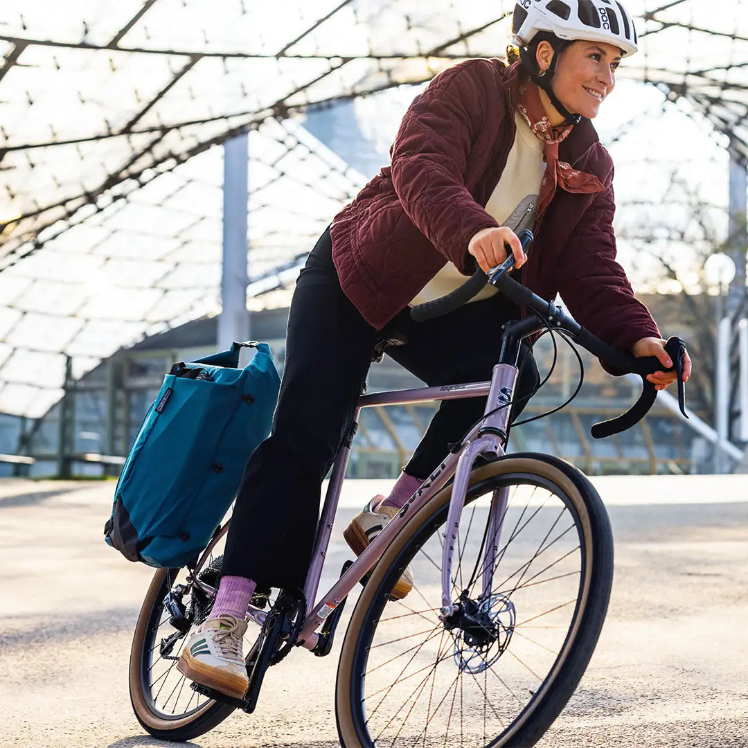 Ortlieb（オルトリーブ）Vario Lite（ヴァリオライト）カラー：ぺトロール　リアキャリアに付けてロードバイクを走行する女性